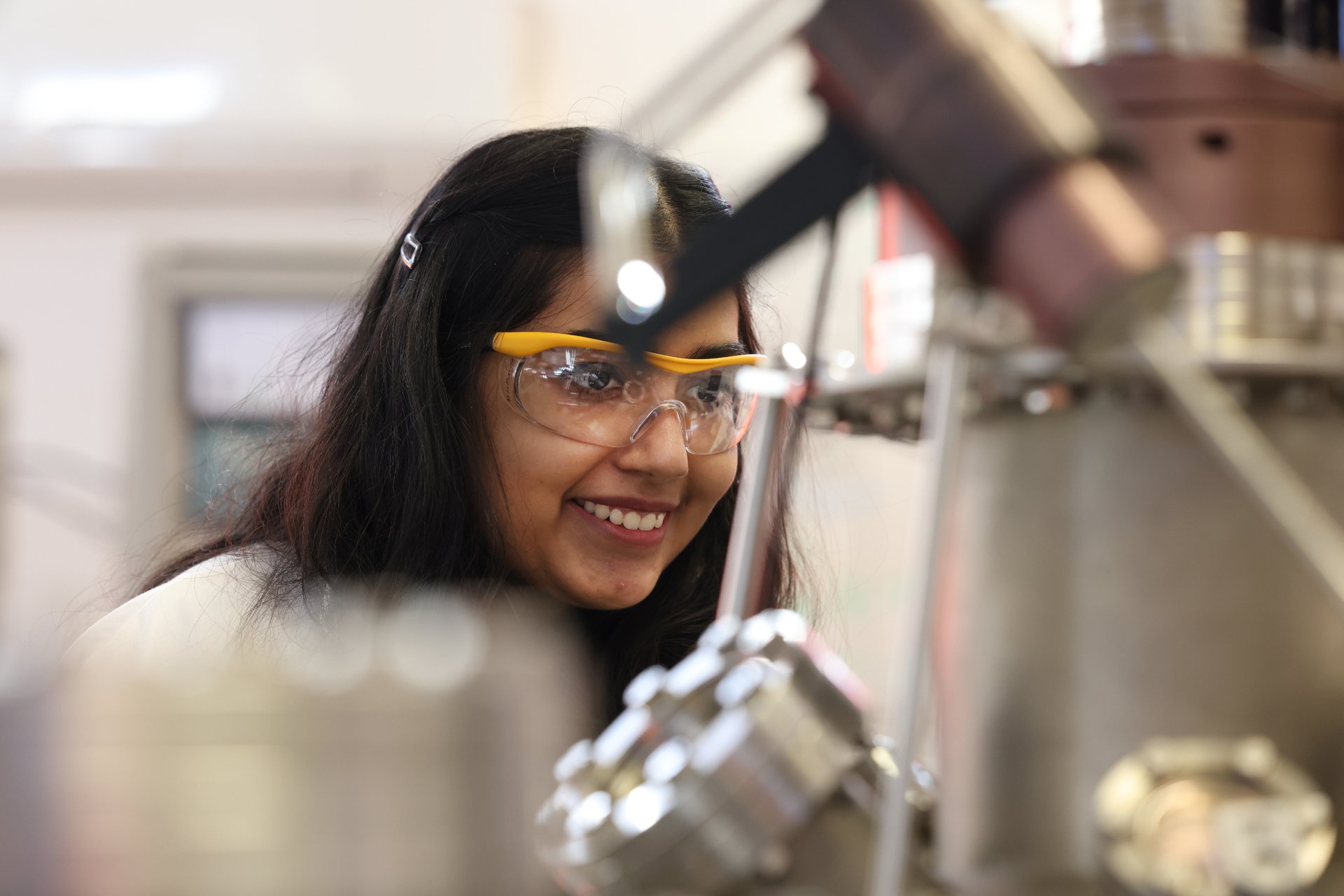 A student wearing safety glasses, using lab equipment.