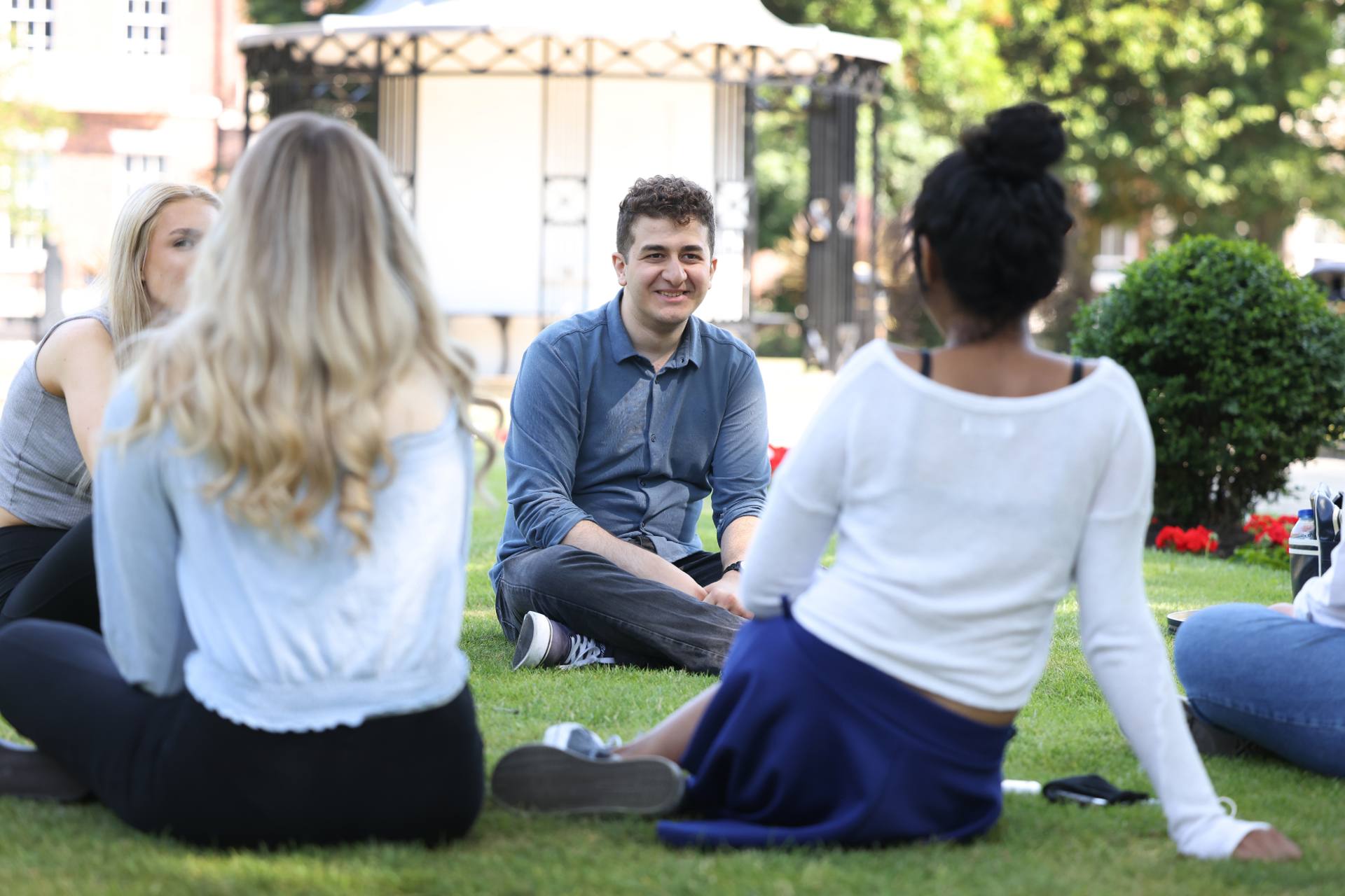 A group of students are sitting on the grass at Abercromby Square on a sunny day.