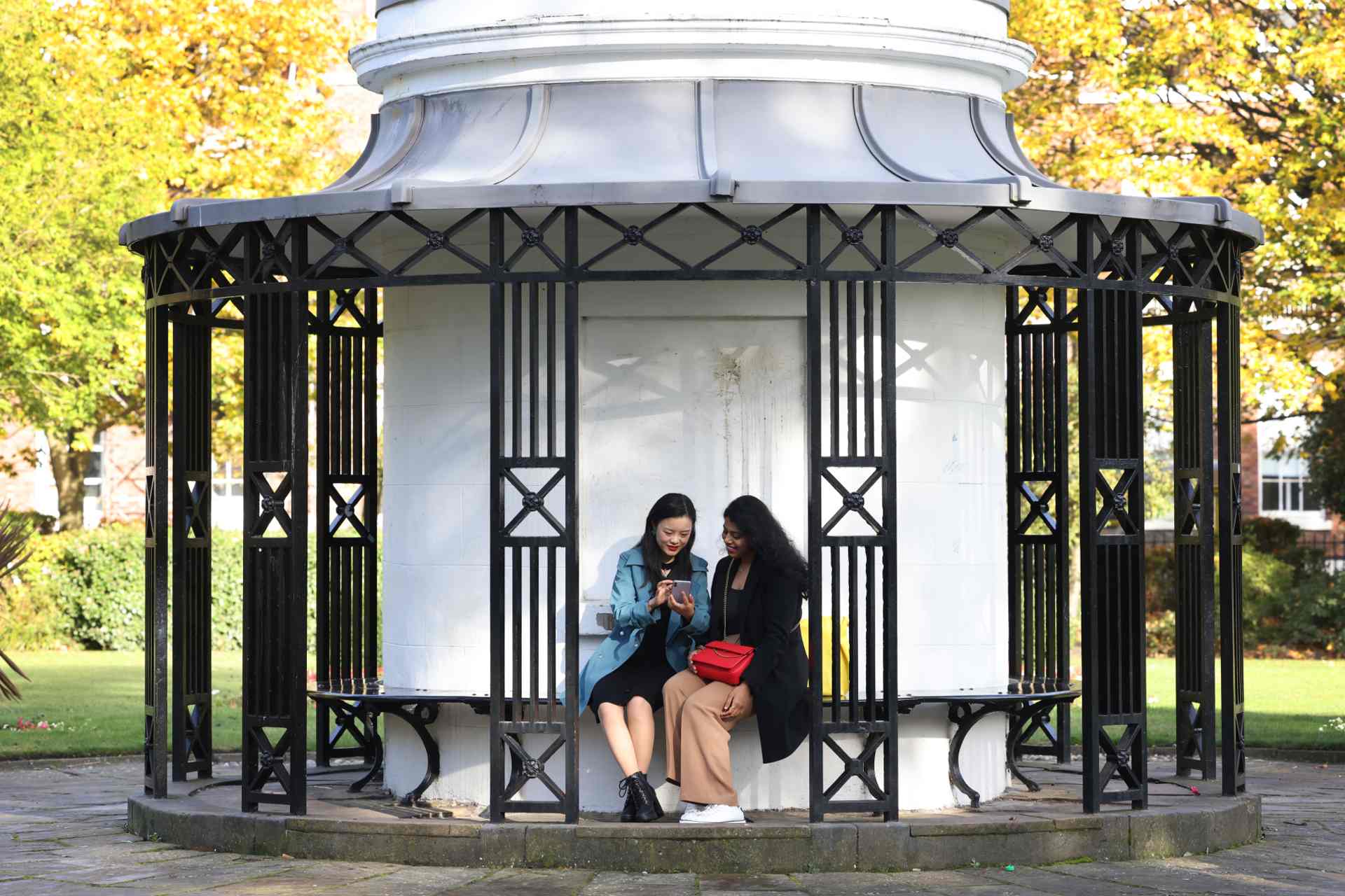 Two students sitting in the sheltered benches on Abercromby Square, talking.