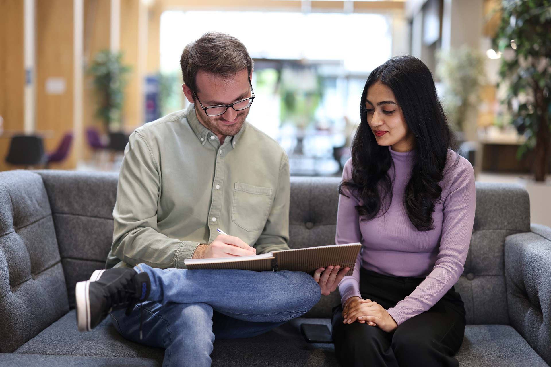 Students Michael Gillin and Saithaini Ithayaaj working together on a couch