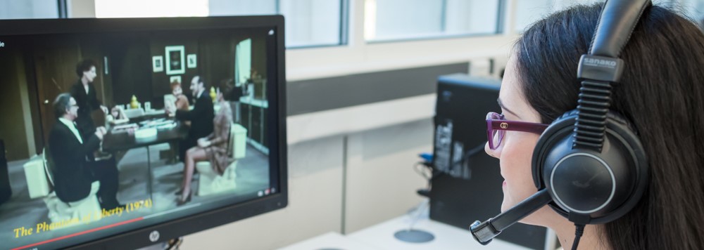 A student wearing headphones looking at a computer screen