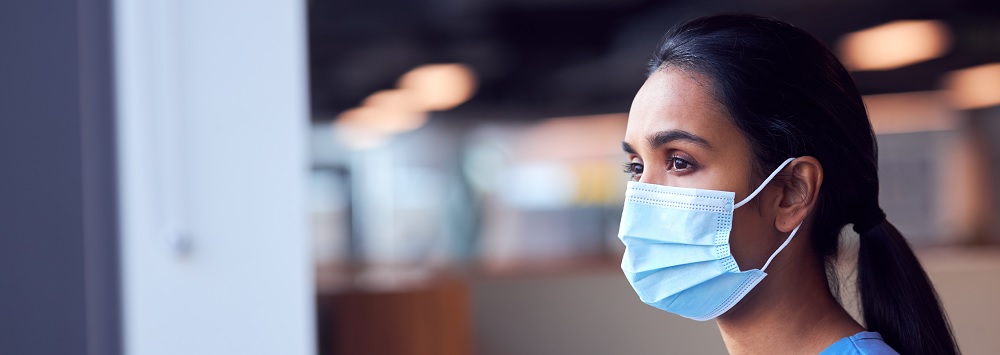 A health professional wears a surgical face mask