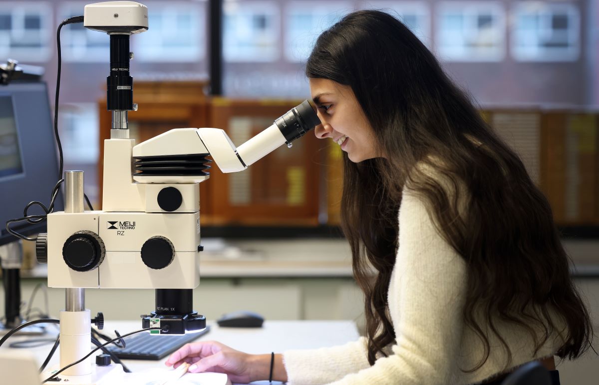 Geography student studying with microscope
