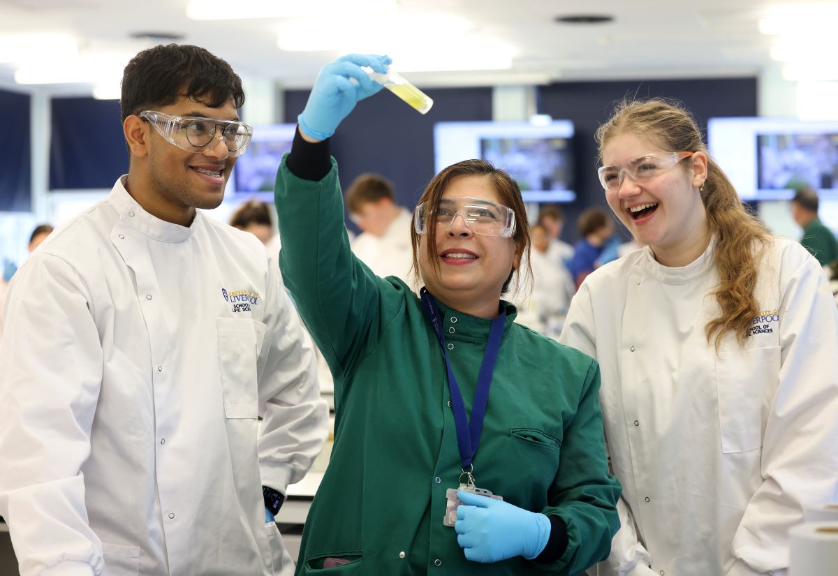 Teacher and students studying a test tube and smiling