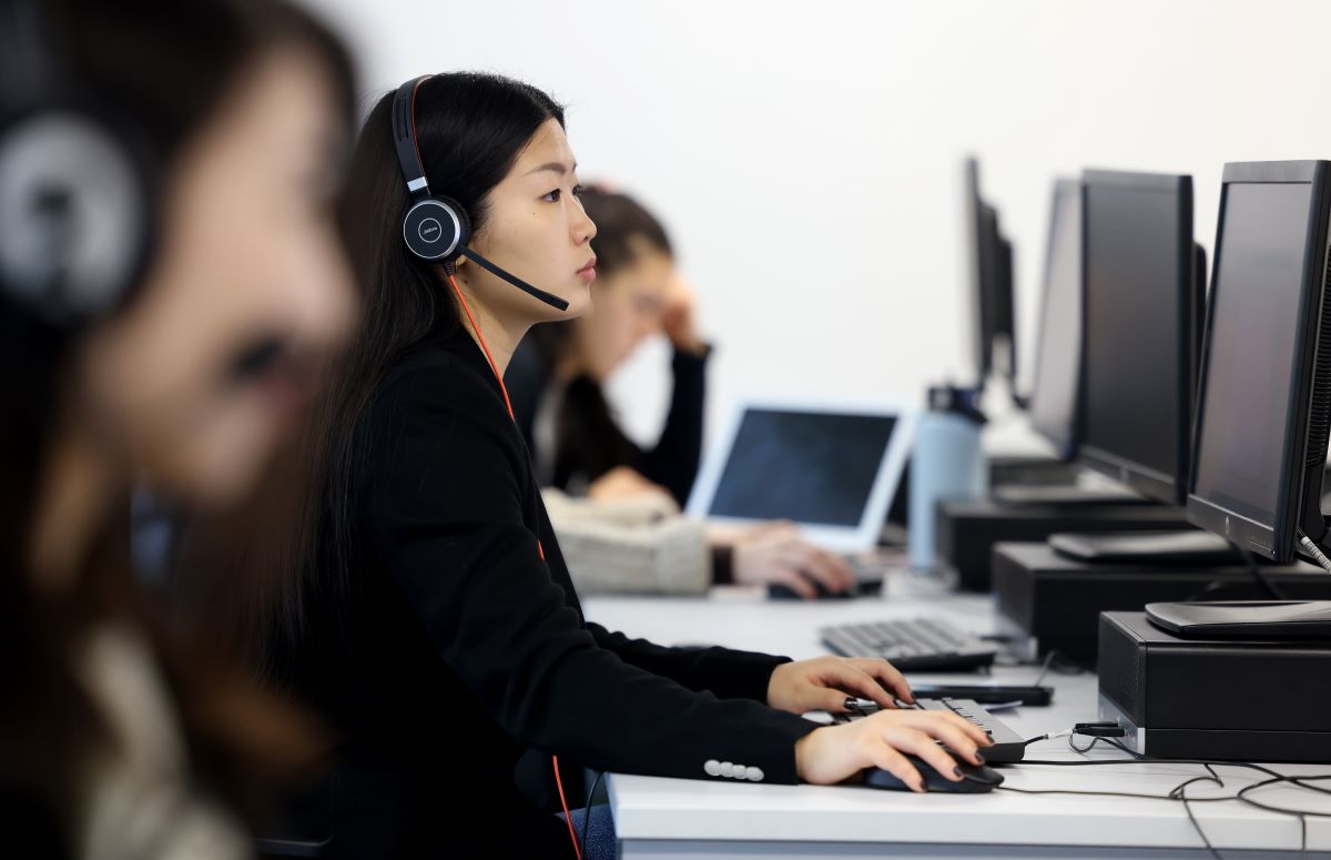 Management student working on computer wearing a headset