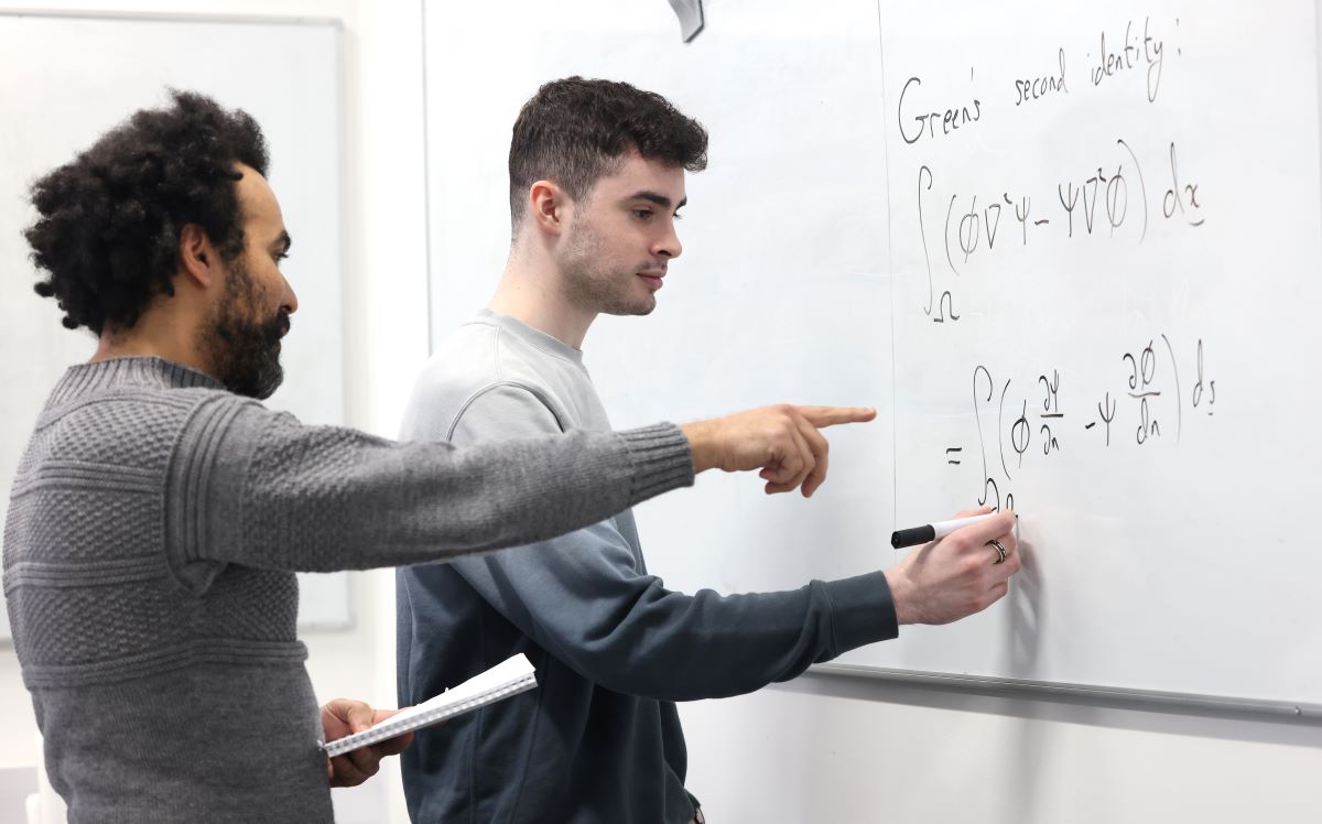 Mathematics teacher and student working on an equation on white board