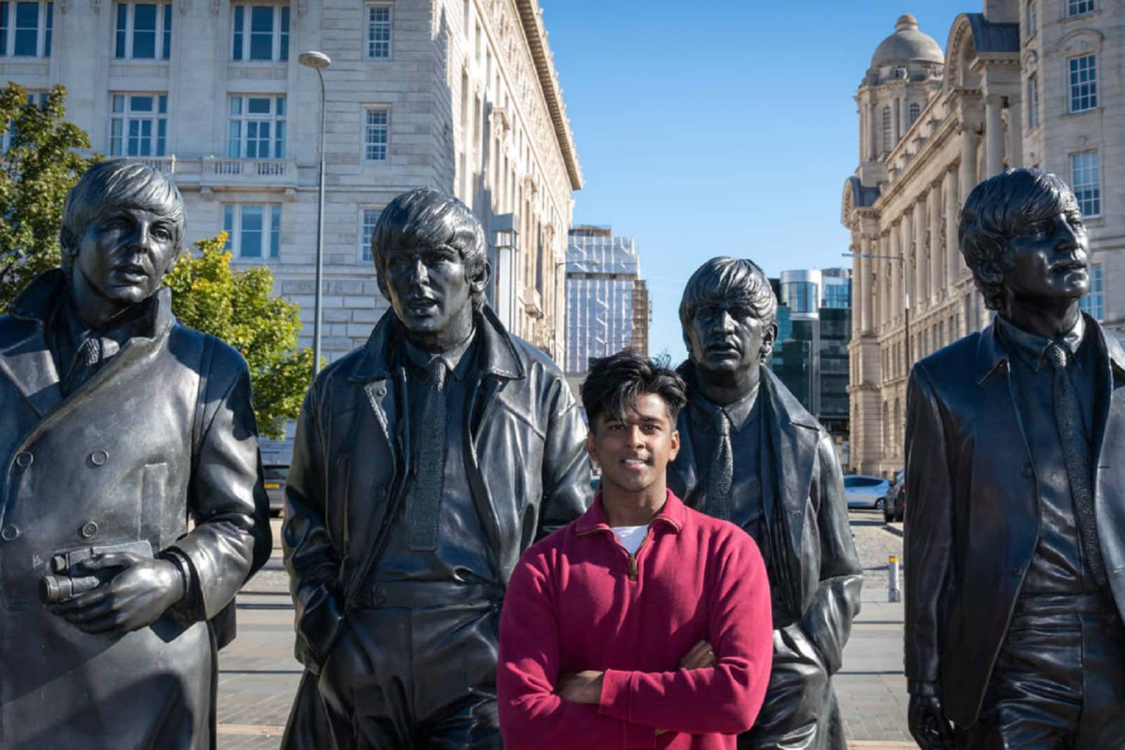 A student stands in front of a sculpture of The Beatles on Liverpool's waterfront