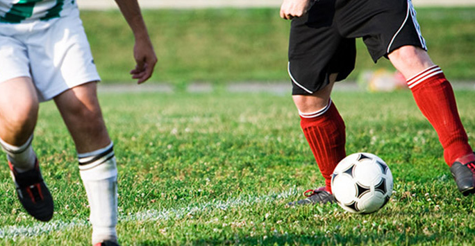 Photograph of the legs of two people playing football