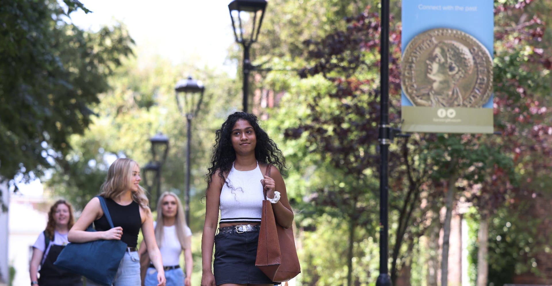 A student walking outside on a sunny day on campus