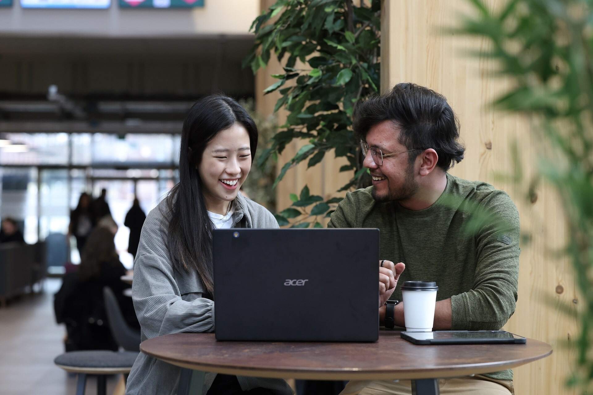 Two students smile and use a laptop together