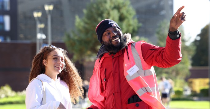 A member of staff giving a visitor directions on an open day