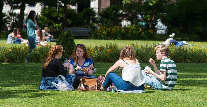 A group of 4 students sat in the shade on a hot summers day in Abercromby Square in Liverpool.
