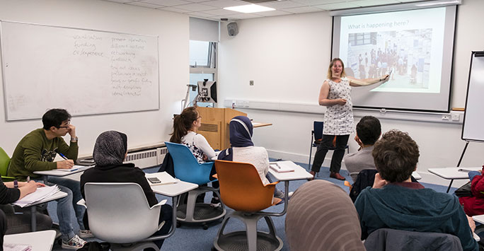 Teachers sat around in a training room receiving a seminar. 