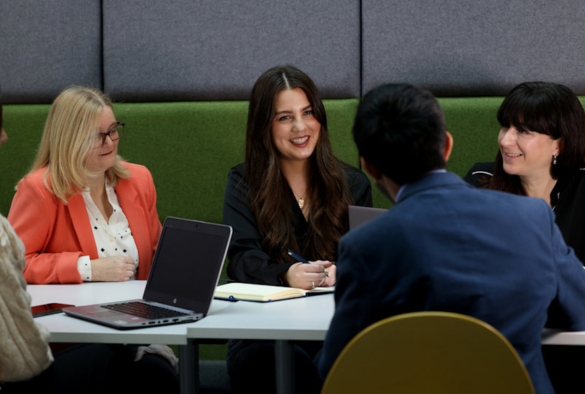 A group of professionals gathered around a table talking and smiling.