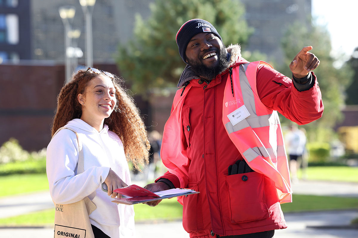 A member of staff in a high visability vest helps a visitor