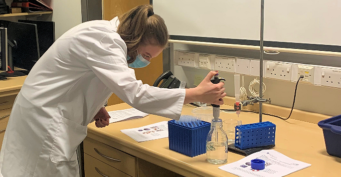 A female A-Level pupil from Range High carrying out an experiment