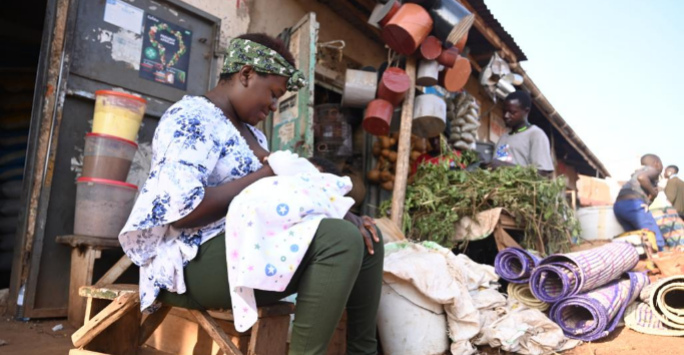 Woman breastfeeding her baby in a market