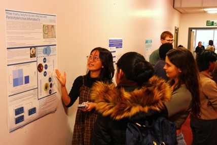 A female student explaining her research via a poster presentation