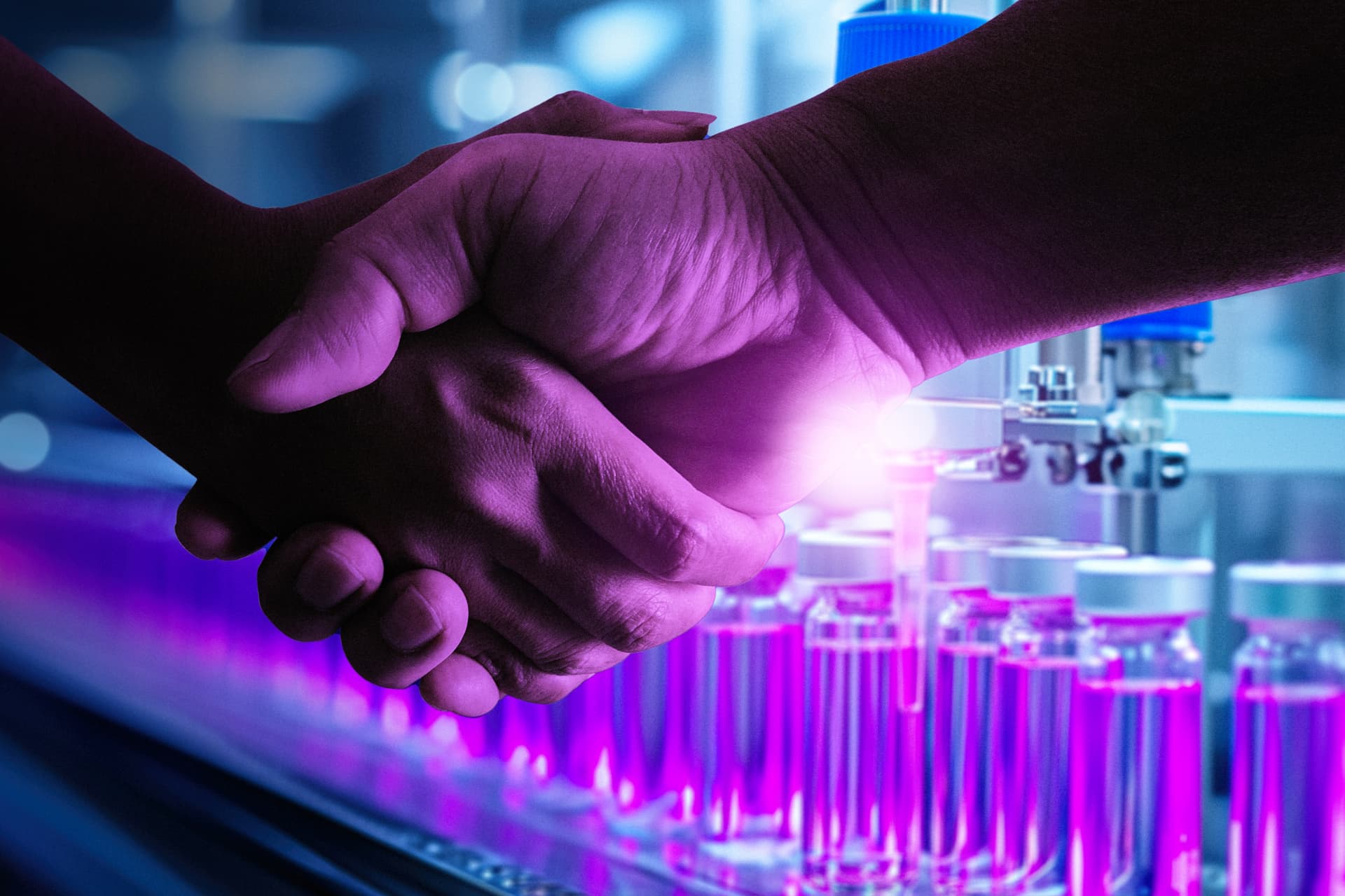 A close-up photo of a handshake, taking place in a laboratory