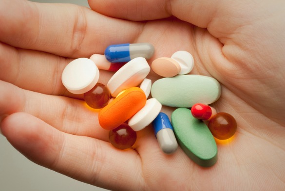 Close up image of a hand holding a variety of different medications