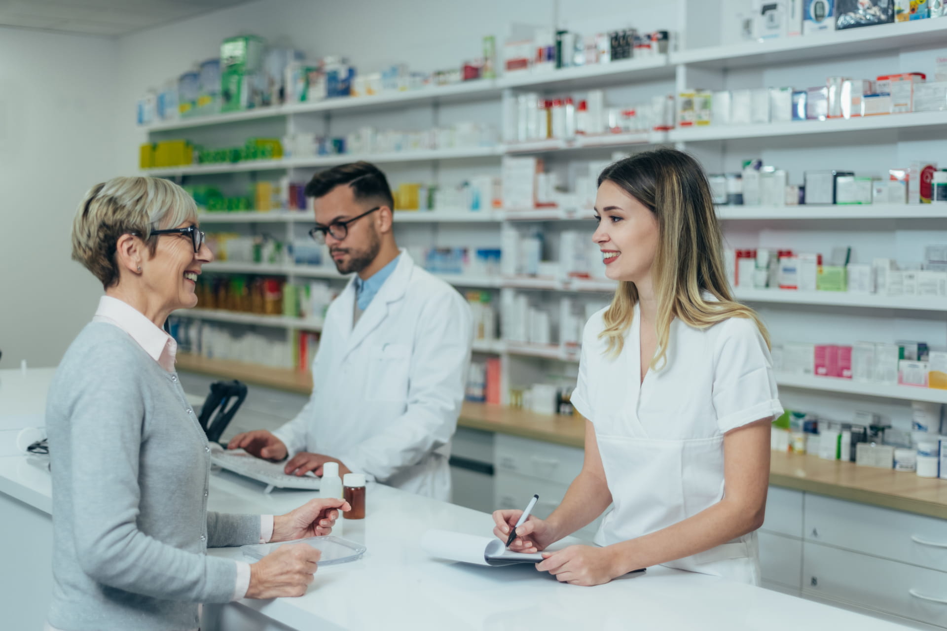 Pharmacist giving prescription medications to smiling senior female customer