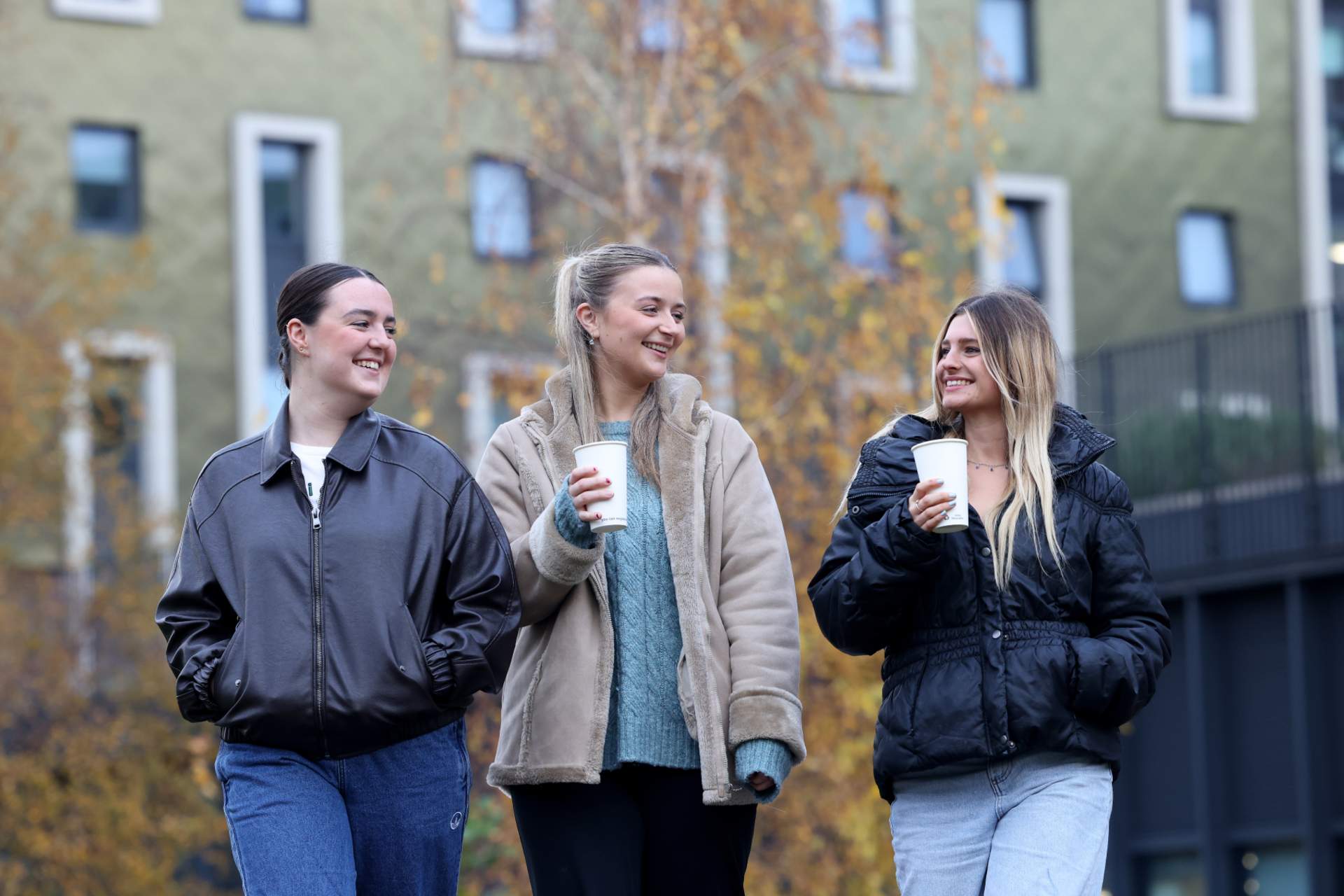 3 students walking and drinking hot drinks.