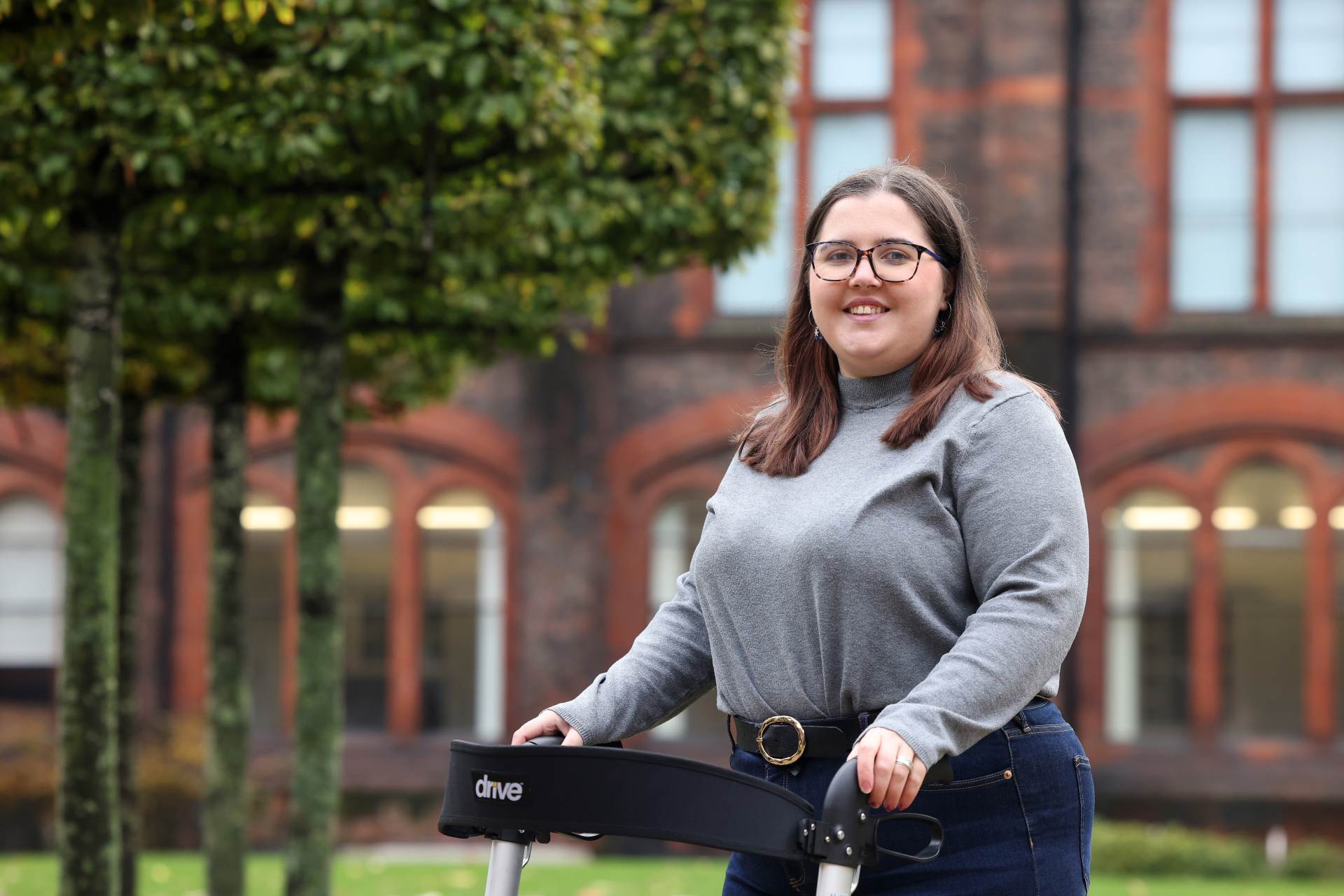 A student smiling using a walking frame