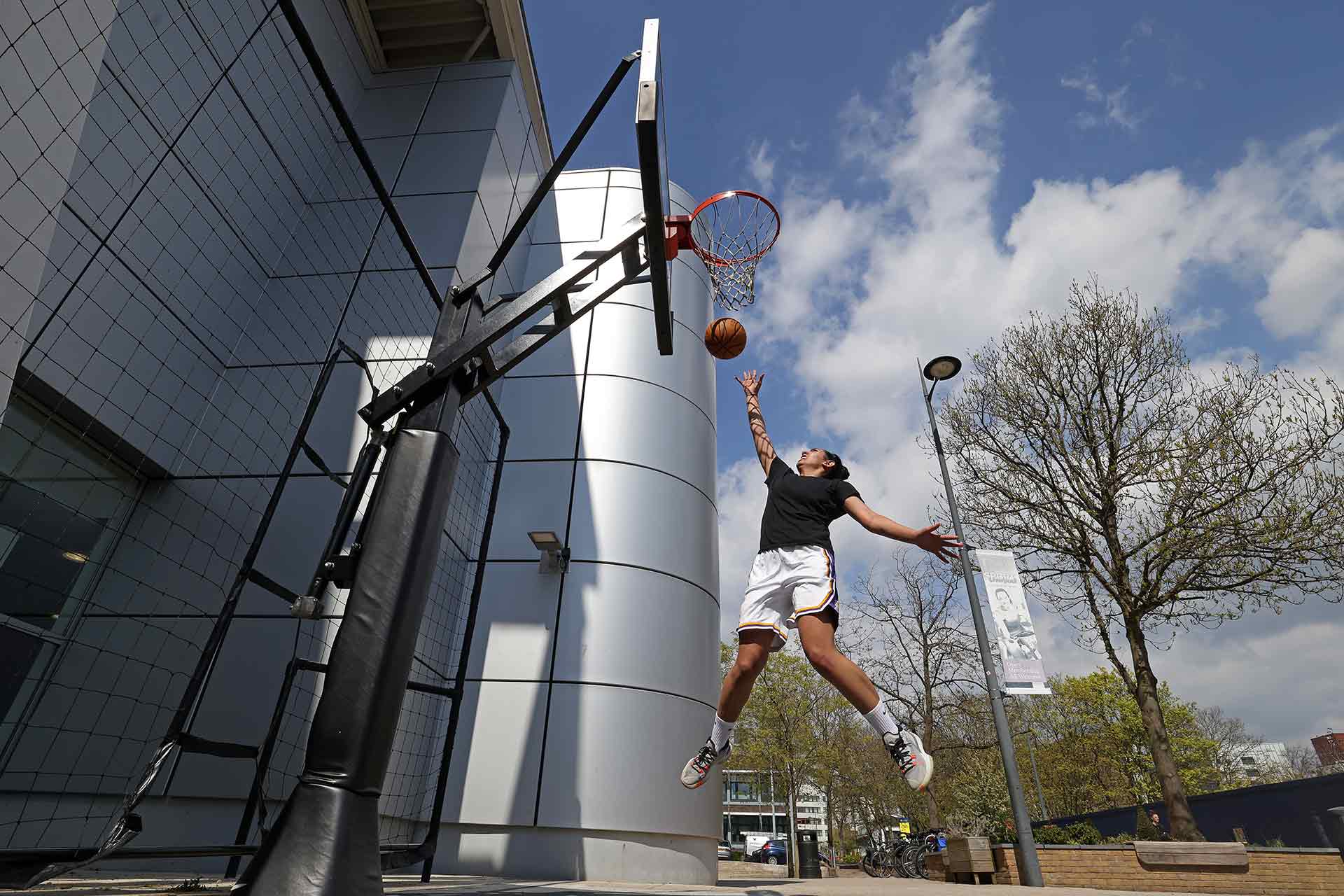 A student playing basketball outdoors on campus.