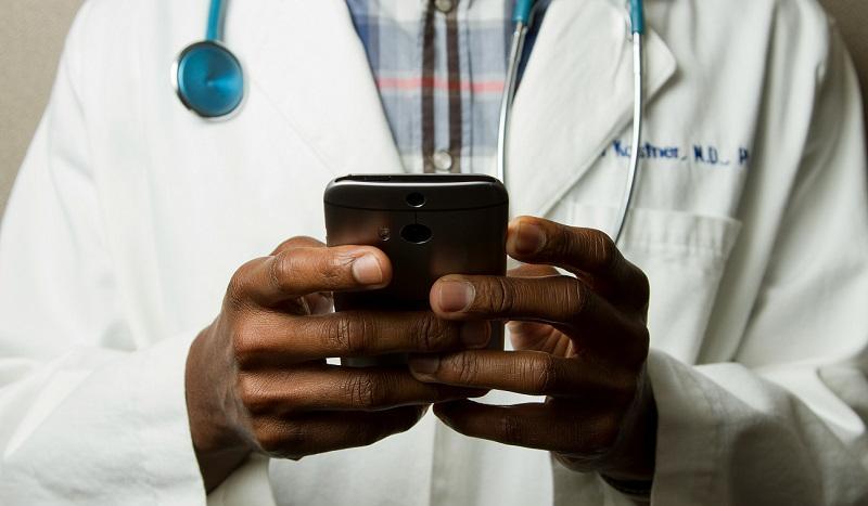 Stock image of a doctor in a white lab coat using a mobile phone
