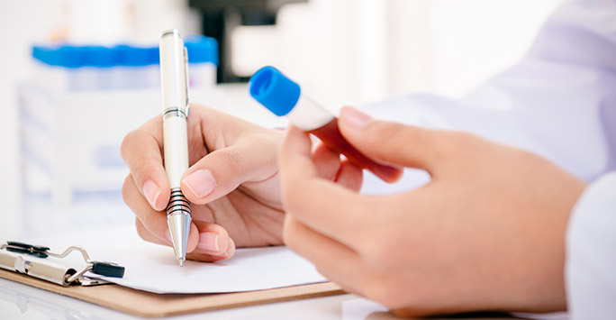 Doctor writing notes about a blood sample