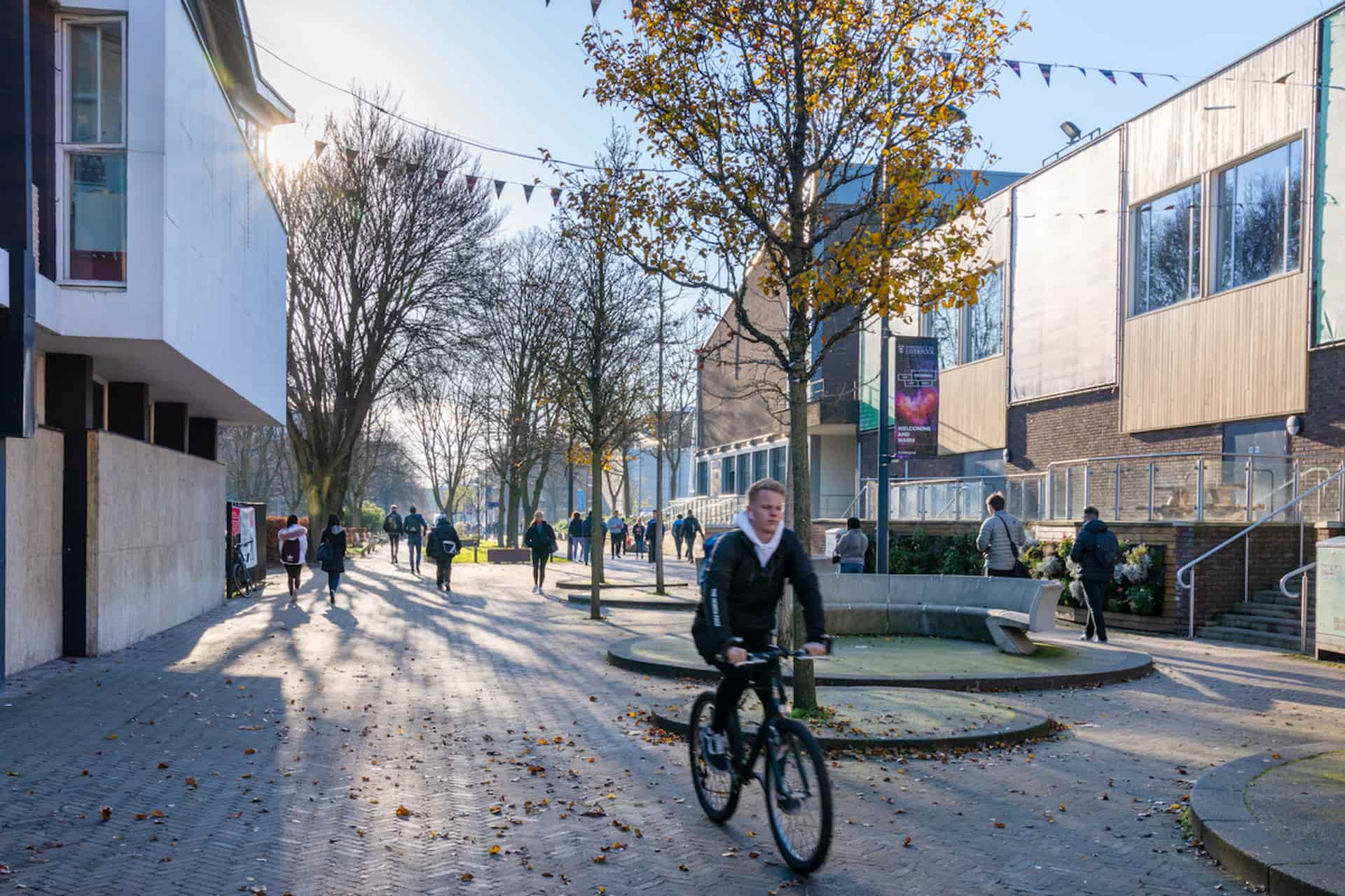 Student cycling through campus on sunny day