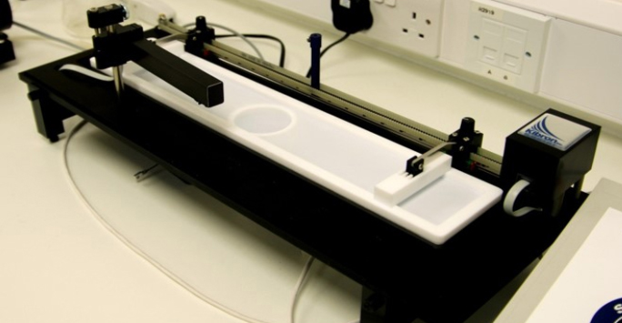 A microscope positioned on a table, illuminated by a bright white light, highlighting its intricate design and features.