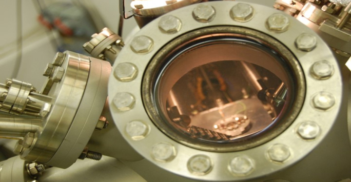 Close-up of a metal machine illuminated by light, highlighting intricate details and textures of the machinery.