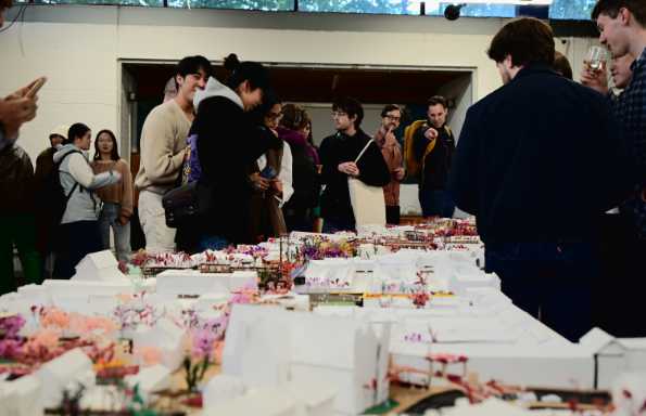 Mixed group of people standing round a table displaying a large architectural model of a town centre