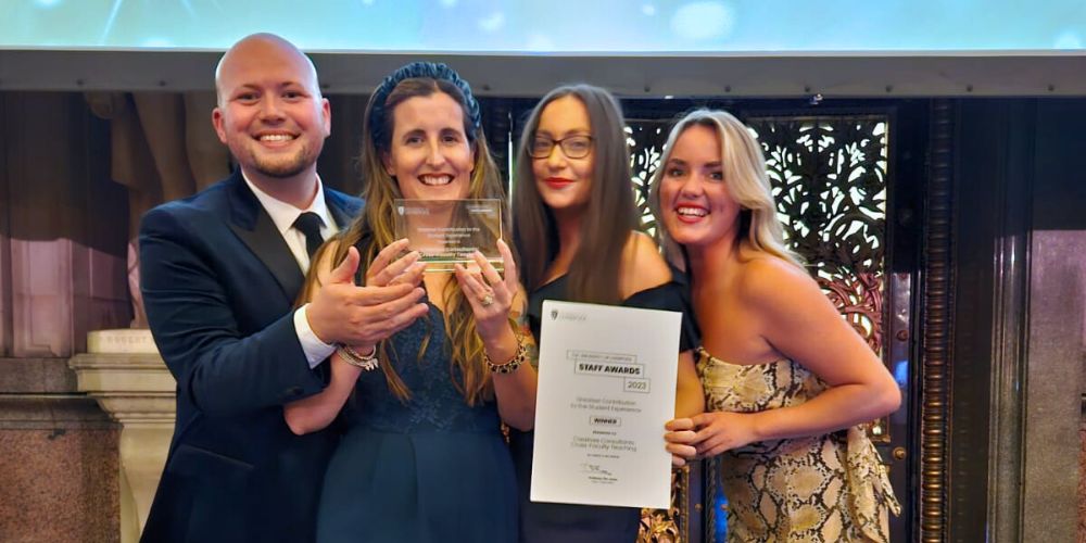 A group of University of Liverpool Careers & Employability staff celebrating an award win, holding a trophy and certificate.