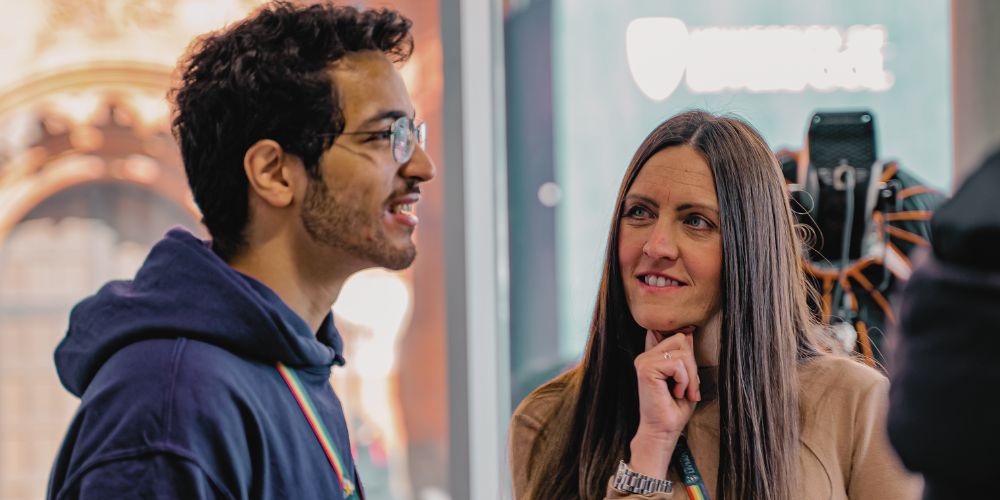 A University of Liverpool careers representative speaking to an coach at a careers event, encouraging collaboration and engagement.