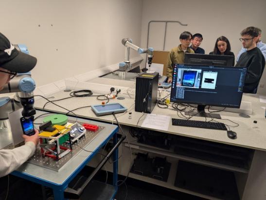 A diverse group of people collaborating in a lab while working on a computer.
