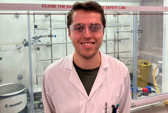 Ross Adams in a lab wearing white lab coat and safety lab goggles