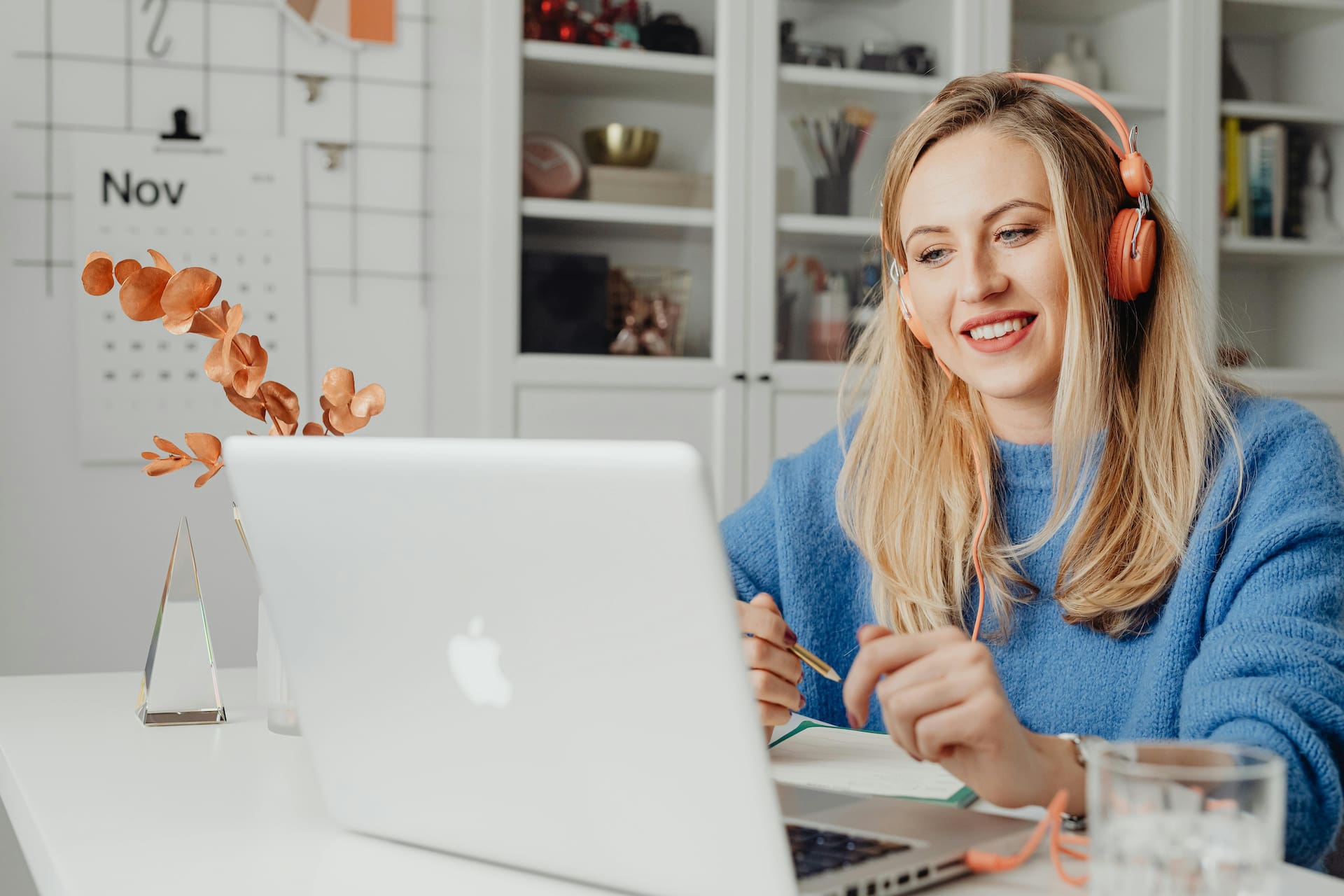 A woman with blonde hair looking at a laptop screen, while wearing headphones.