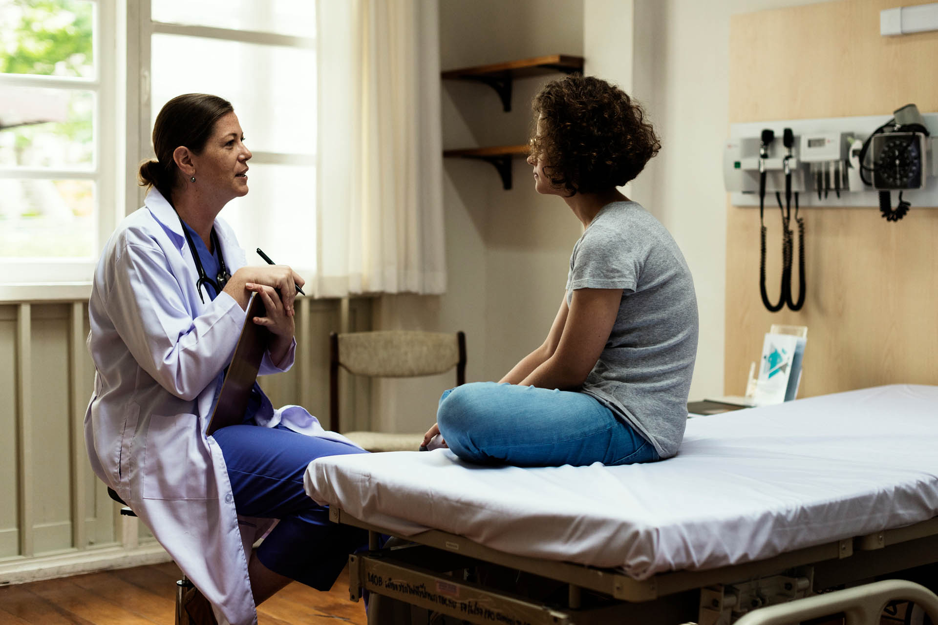 Doctor sitting talking to a patient on a hospital bed