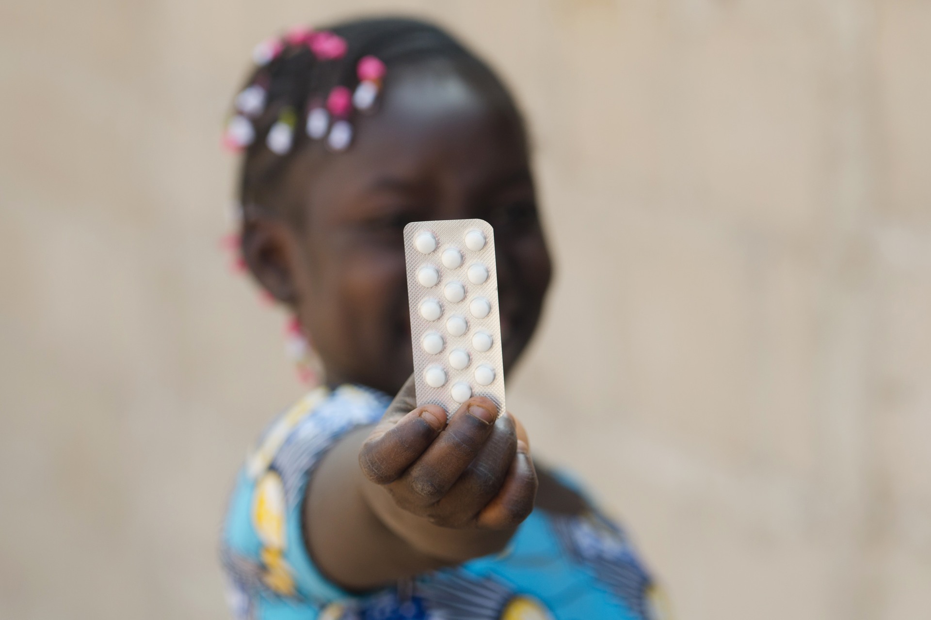 Young African girl holding a packet of medicine