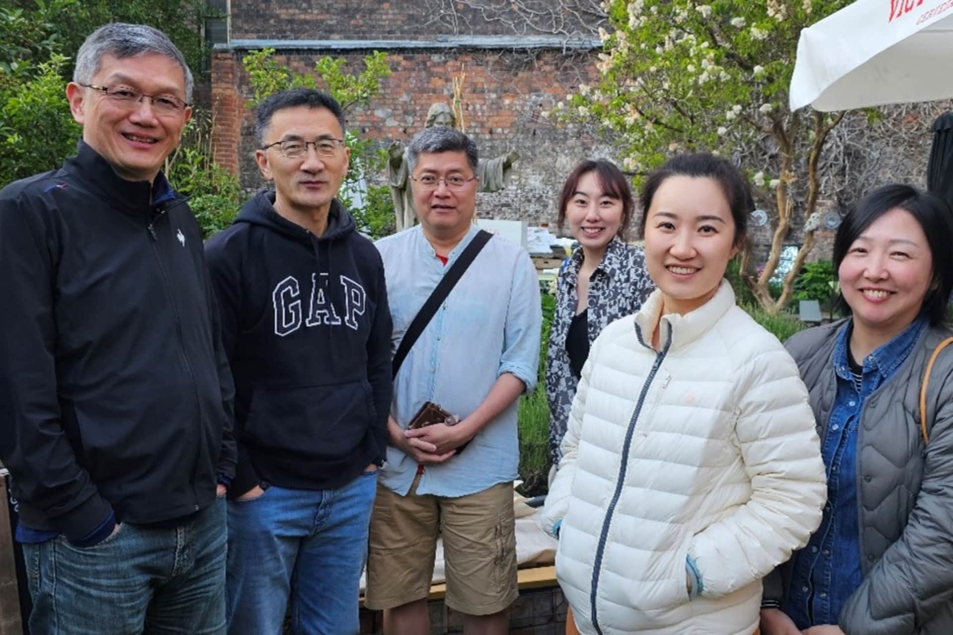 Group of six people stood together smiling at camera in a garden setting