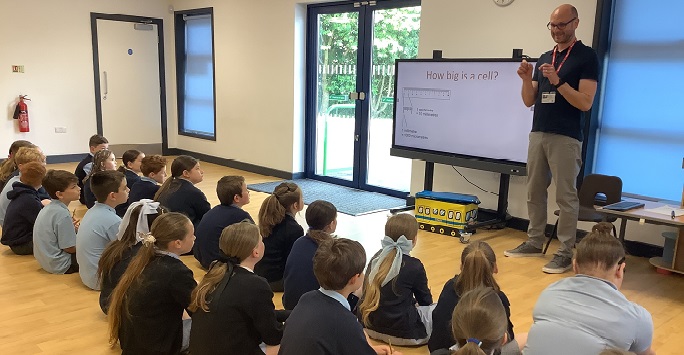 Primary school students sat on the floor listening to a presentation