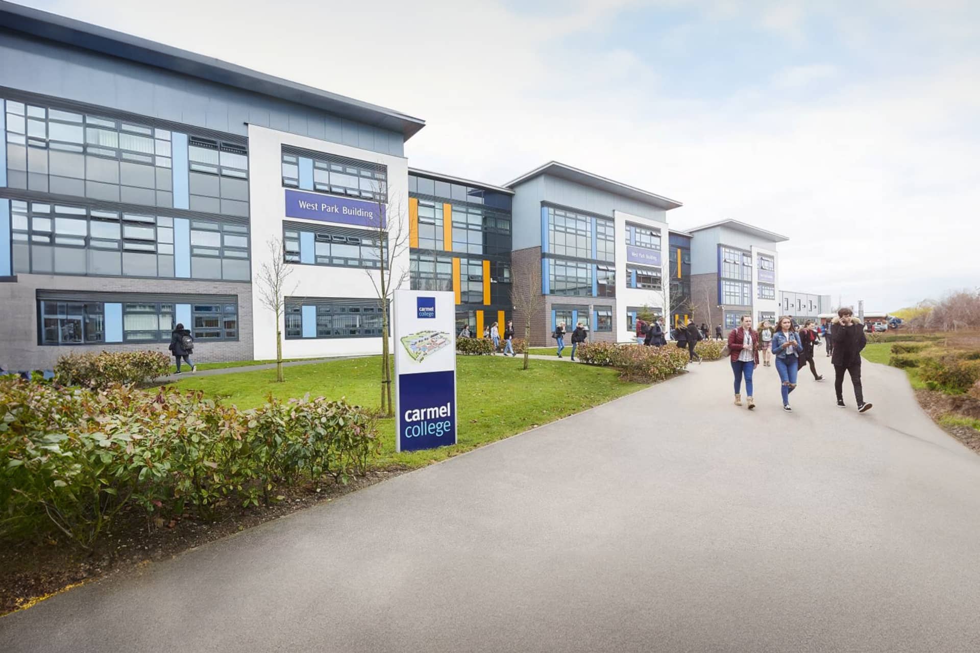 The exterior of a Carmel College building, students walking from the entrance