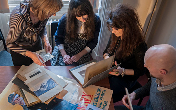 Students and academics looking at media around a table