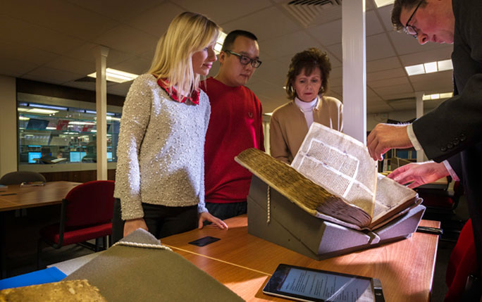 People examining and leafing through an old document