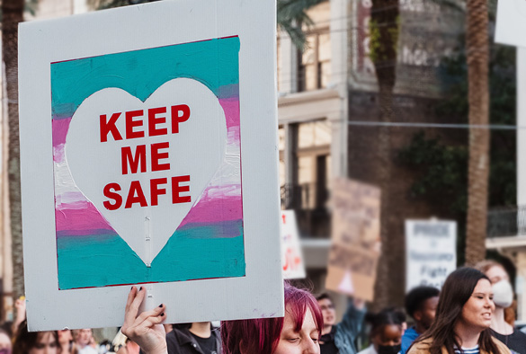 Crowd marching with sign that reads \'Keep me safe\'.