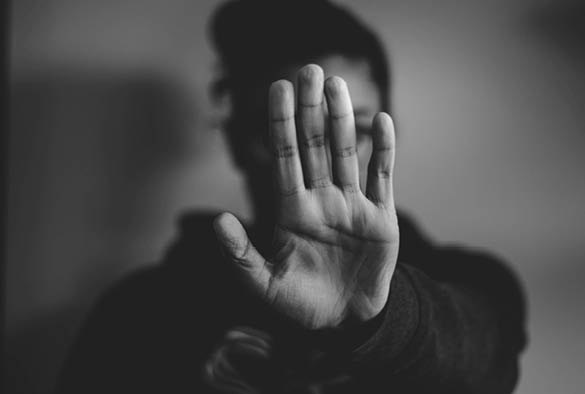A photograph in black and white of a girl holding up their hand to say stop.