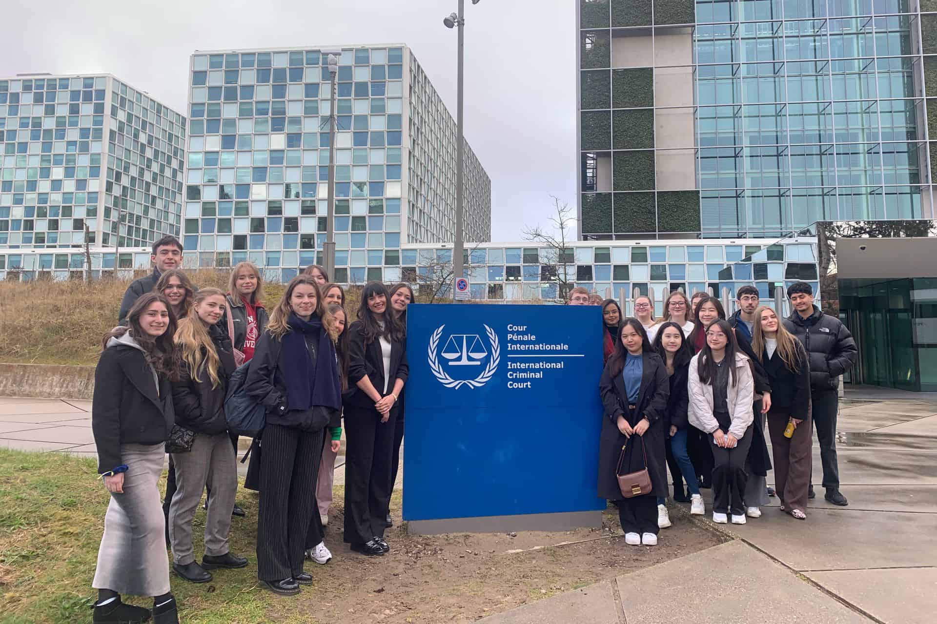 The students from the study trip stand together in front of the International Criminal Courts building.