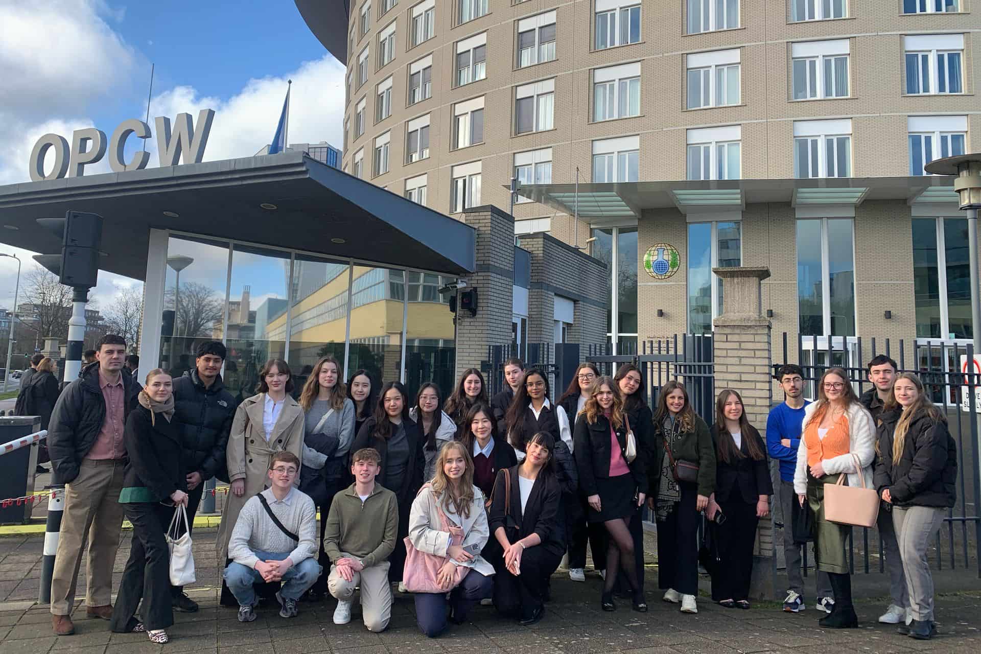 The students from the study trip stand together in front of the OPCW building.